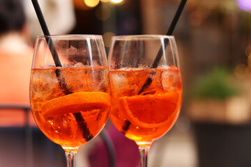 Aperol Spritz. Cold refreshing alcoholic cocktail Aperol Spritz. Cocktail close-up on a blurred background. Alcoholic drink in a glass with a straw. Traditional Italian alcoholic refreshing drink