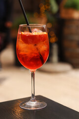 Aperol Spritz. Cold refreshing alcoholic cocktail Aperol Spritz. Cocktail close-up on a blurred background. Alcoholic drink in a glass with a straw. Traditional Italian alcoholic refreshing drink