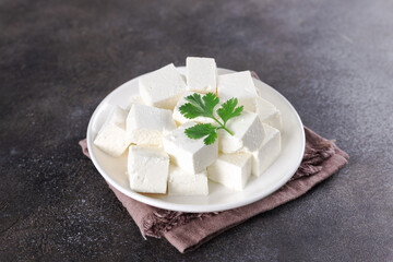 Cubes of Indian paneer cheese on dark background. Indian food.
