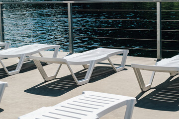 Obraz premium Serene lakeside relaxation with white loungers under gentle sunlight