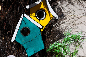 Colorful birdhouses nestled among twigs create a vibrant outdoor decor