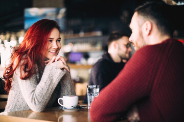 Beautiful young couple having coffee and using smart phone