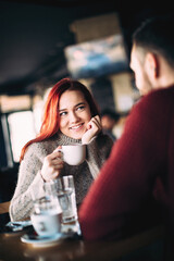 Beautiful young couple having coffee and using smart phone
