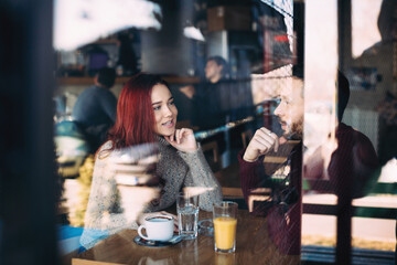 Beautiful young couple having coffee and using smart phone