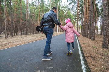 Obraz premium Father and daughter riding skateboards in the forest.