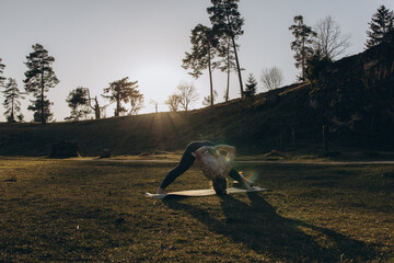 Young woman practicing yoga on nature. Girl meditating outdoors. Female with slim, strength and...