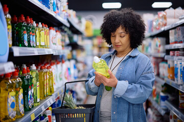 Mature woman reading label on product while shopping in supermarket.