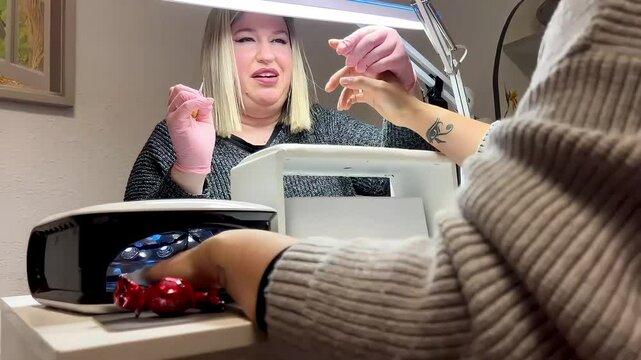 Beautician applying nail polish on client's hands