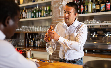 Bartender shaking cocktail for friends, they drinking in nightclub