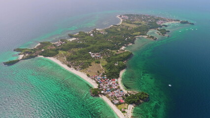Aerial view of Malapascua Island in the Philippines, featuring vibrant turquoise waters, lush tropical vegetation, and colorful houses along the picturesque coastline