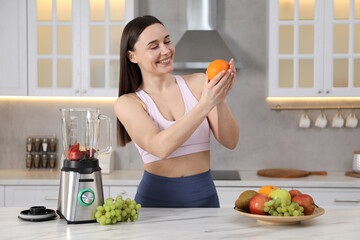 Woman in fitness clothes with orange at white marble table indoors