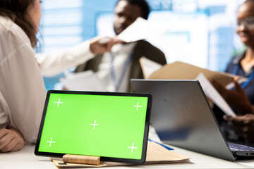 Marketing team reviews performance metrics next to green screen on tablet, leveraging big data...