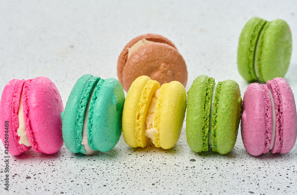 Poster an assortment of colorful macarons on a white surface with dark speckles. the macarons have a smooth