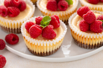 Classic New York cheesecakes in individual cups topped with fresh raspberry