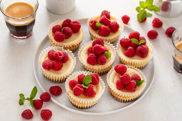 Classic New York cheesecakes in individual cups topped with fresh raspberry