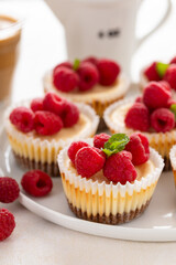 Classic New York cheesecakes in individual cups topped with fresh raspberry