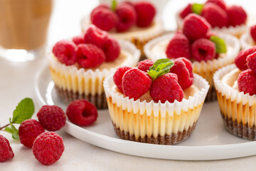 Classic New York cheesecakes in individual cups topped with fresh raspberry