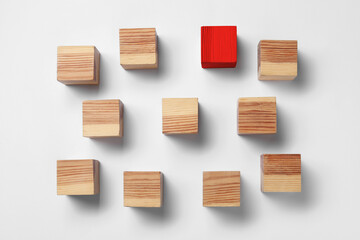 Red cube among wooden ones on white table, flat lay. Different, unique, special