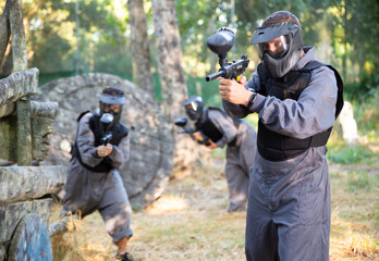 Fototapeta premium Man eliminating opponents on paintball field. Man in protective outwear and helmet targeting with paintball marker.