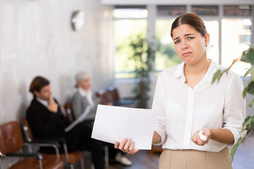 Frustrated disappointed young businesswoman standing in office helplessly spreading her arms....