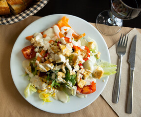 Appetizing Caesar salad with tomatoes, corn, olives and fried chicken