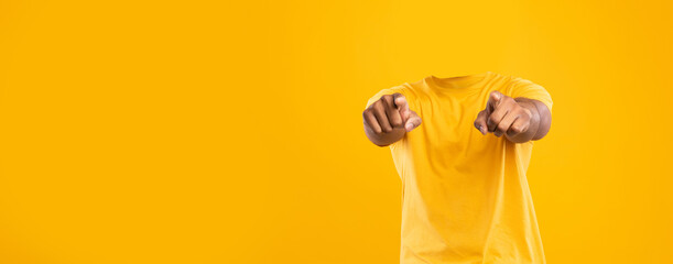 Headless individual is seen pointing toward the viewer against a bright yellow background. This isolated lifestyle portrayal emphasizes blank space and brings a unique perspective.