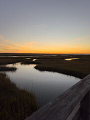 Tranquil Sunset Over Coastal Marsh Viewed from Wooden Railing