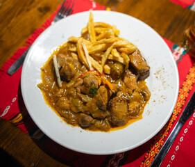 Stewed pork with mushrooms and French fries on a white plate, top view. Delicious stew for lunch