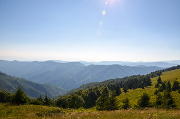 Beautiful view of a lush green mountain range under a clear blue sky with sunlight. Tranquility of...