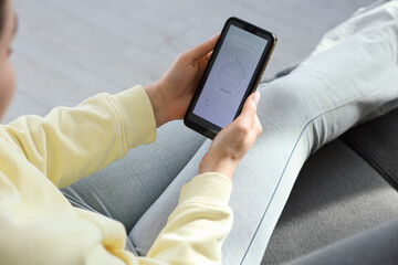 Menstruation. Woman using period calendar application on smartphone indoors, closeup