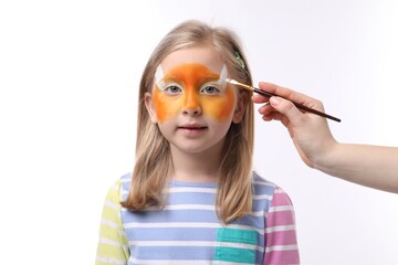 Animator drawing fox on girl's face against white background, closeup