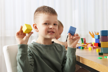 Cute boy with colorful cubes at desk in school