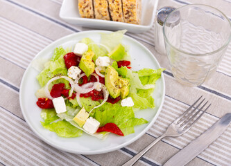 Appetizing salad of fresh vegetables with pim cheese, avocado and onion served on platter