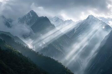 Majestic mountain range illuminated by rays of sunlight amidst dark storm clouds during early morning