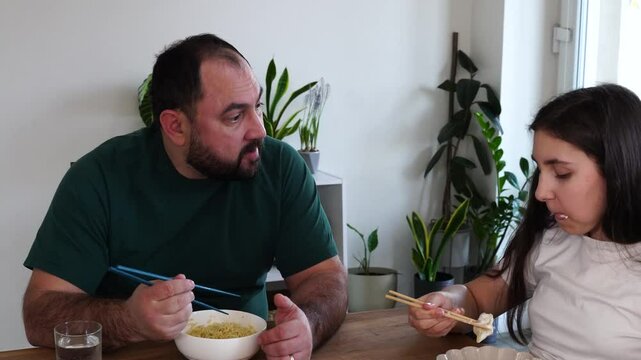 Father and daughter are eating asian food at home