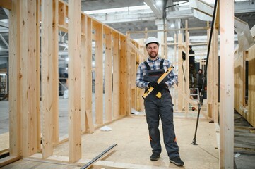 Portrait of a young carpenter worker in a helmet at the construction site of modular houses