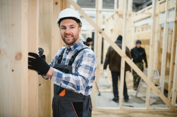 Construction of modular houses. Male construction worker in uniform and hard hat at construction...