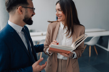 Businesspeople smiling and discussing content in a book
