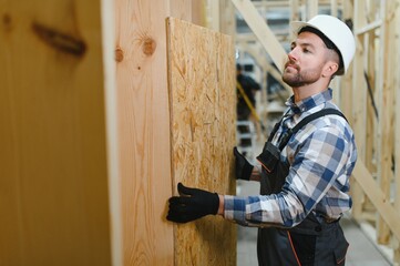 Construction of modular houses. Male construction worker in uniform and hard hat at construction...