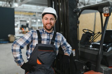 Portrait of a smiling forklift driver wearing a hardhat while working on the the floor of a carpet...