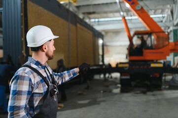 Foreman manages the loading of a prefabricated modular house to truck using walkie talkie