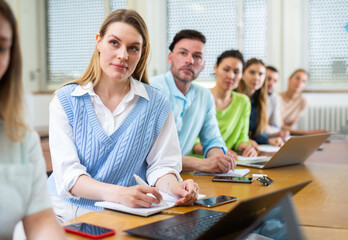 Female senior student listening lecture in class room. Students sitting in row.