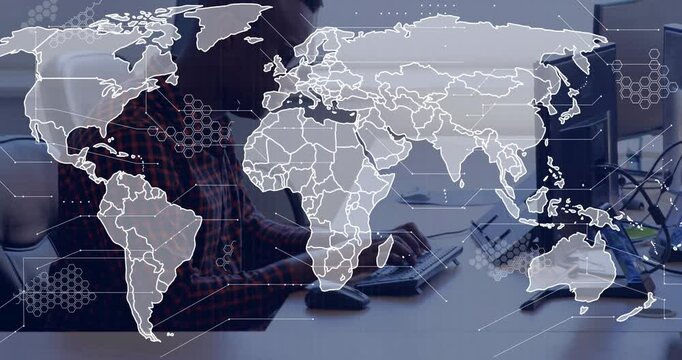 Software developer typing at keyboard in modern office, overlaying global map with hexagon data
