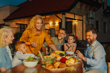 Happy family enjoying outdoor dinner together in backyard