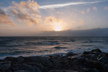 The ocean is calm and the sky is a beautiful orange color