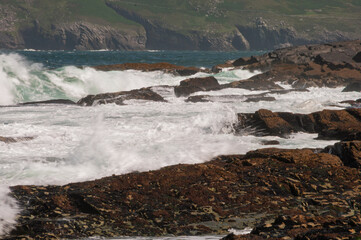 The ocean is rough and the waves are crashing against the rocks