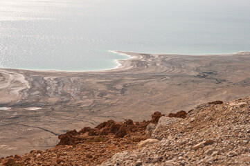 A rocky, barren landscape with a body of water in the background