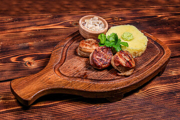 Angled View: Bacon Wrapped Medallions with Puree and Mushroom Sauce on Dublin Wooden Board, Dark Table