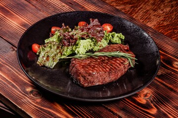 Culinary Elegance: Grilled Steak with Sprig of Rosemary, Served with Light Salad on Black Plate Against Warm Wooden Table Background, Creating Exquisite Atmosphere.