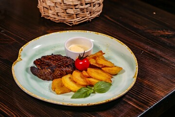 Appetizing Steak with Golden Potatoes, Sauce and Garnish on Textured Plate Featuring Woven Basket, Creating Culinary Charm on Wooden Table.